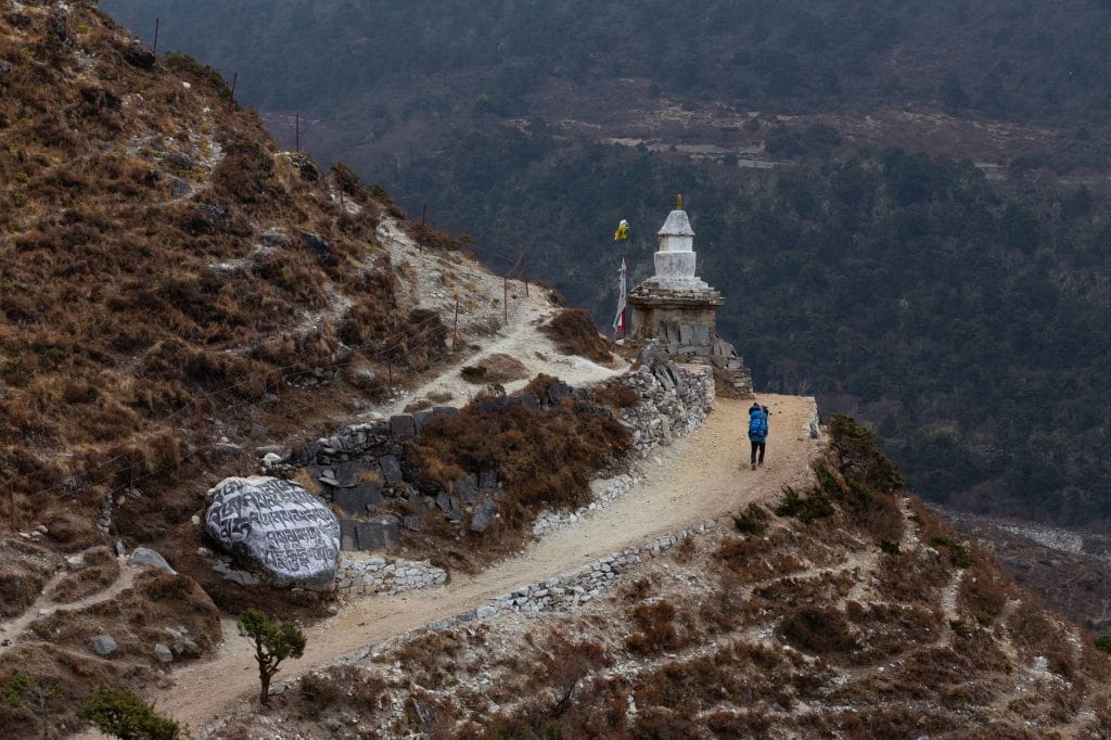 02_A_lone_trekker_walks_a_winding_mountain_trail_beside_a_Buddhist_stupa_